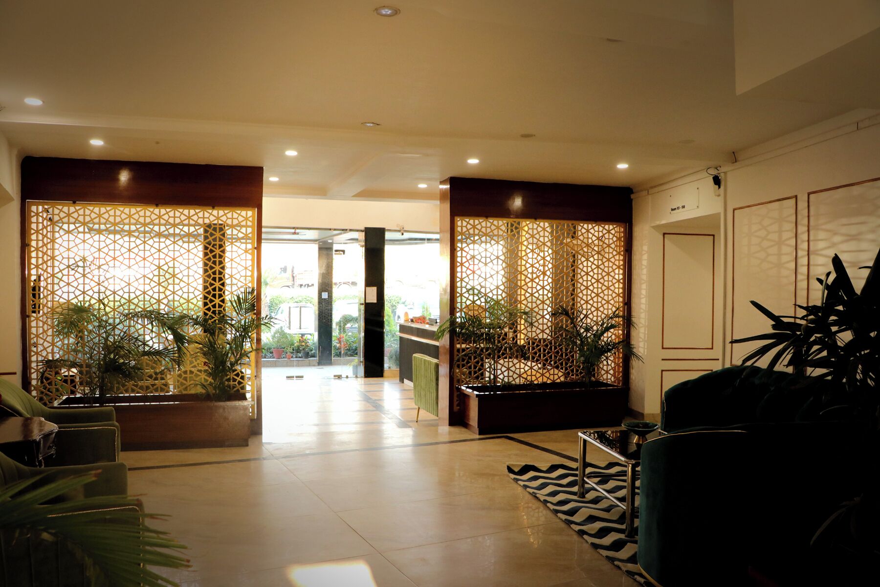 Vestíbulo de hotel con recepción, zona de estar y separadores decorativos.