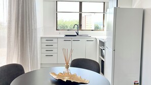 Una cucina moderna con mobili bianchi, un frigorifero e una finestra con vista.