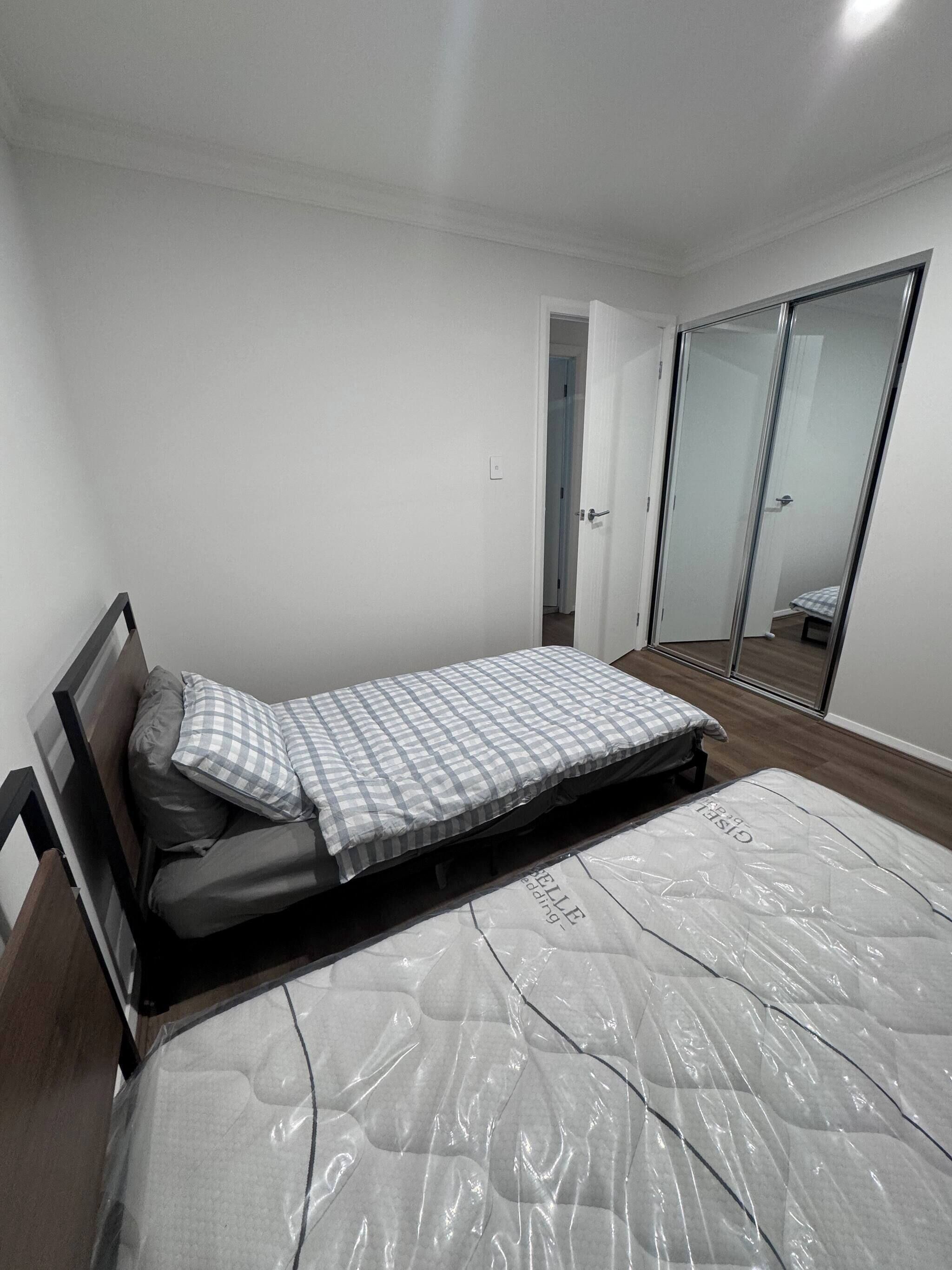 A bedroom with a bed, a wardrobe, and a door leading to another room.