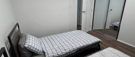 A bedroom with a bed, a wardrobe, and a door leading to another room.