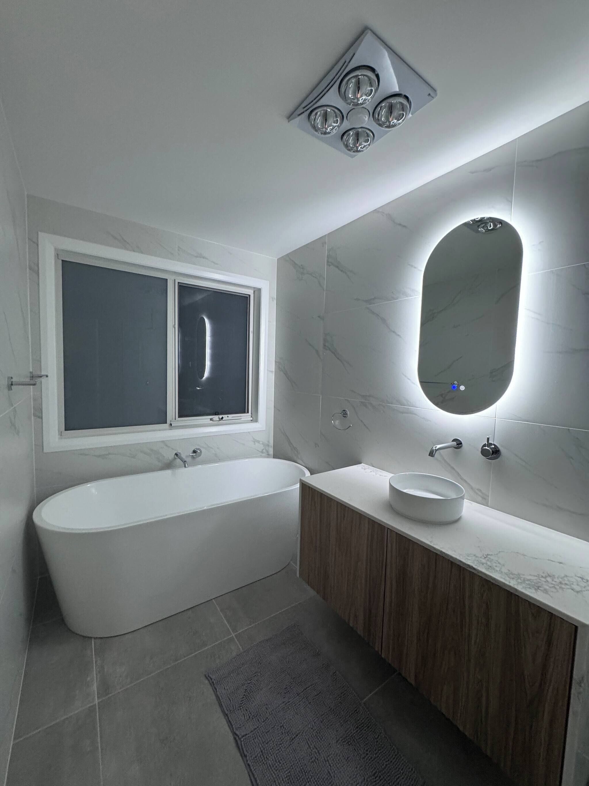 A modern bathroom with a freestanding bathtub, a vanity with a sink, and a large mirror.