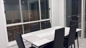 Ein Essbereich mit Tisch und Stühlen, großen Fenstern und Blick ins Freie.