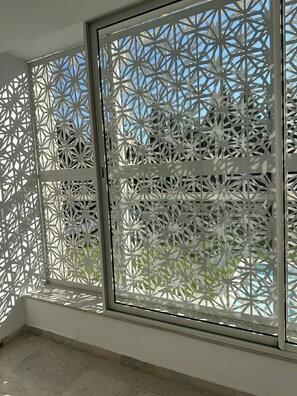 Ein Zimmer mit einem großen Fenster und einem geometrisch gemusterten Sichtschutz.