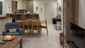 Ett modernt vardagsrum med en matplats, en tv och ett kök i bakgrunden.