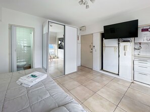 Een hotelkamer met een bed, een flatscreen-tv aan de muur, een koelkast en een magnetron.