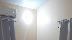 Ein Schlafzimmer mit Bett, Vorhängen, einer Klimaanlage und einer Lampe.