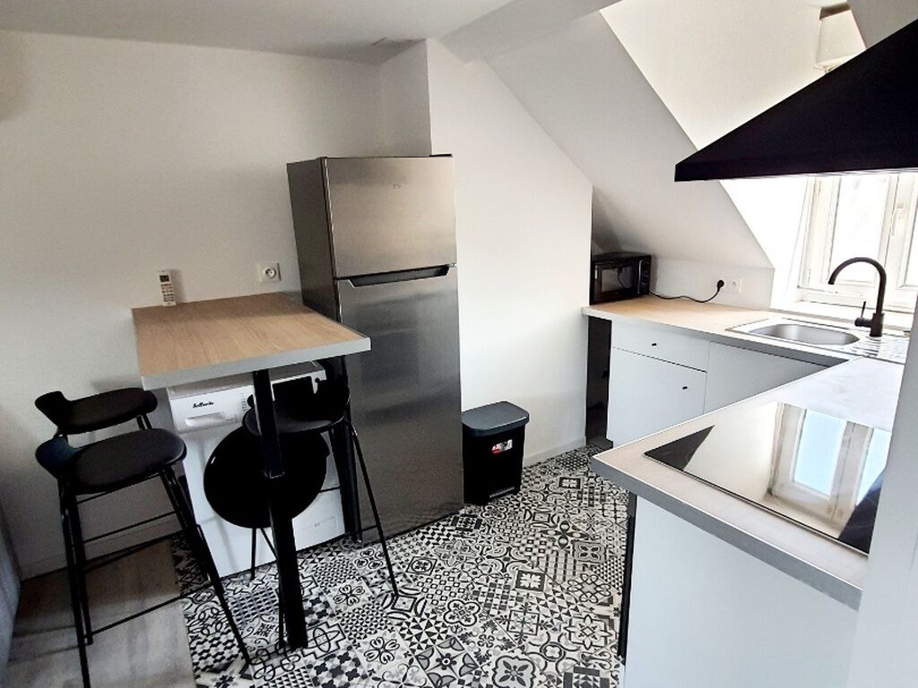 Una cocina compacta con refrigerador, microondas, lavamanos y un ventanal pequeño.