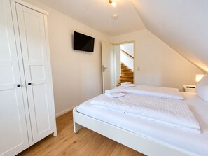 Un dormitorio con cama, armario, televisor y escalera.
