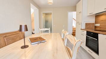 Una cocina moderna con una mesa de madera, sillas blancas y un horno empotrado.