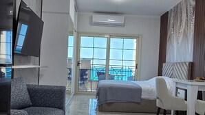 Een moderne woonkamer met een bank, een televisie, een eettafel en een balkon met uitzicht.