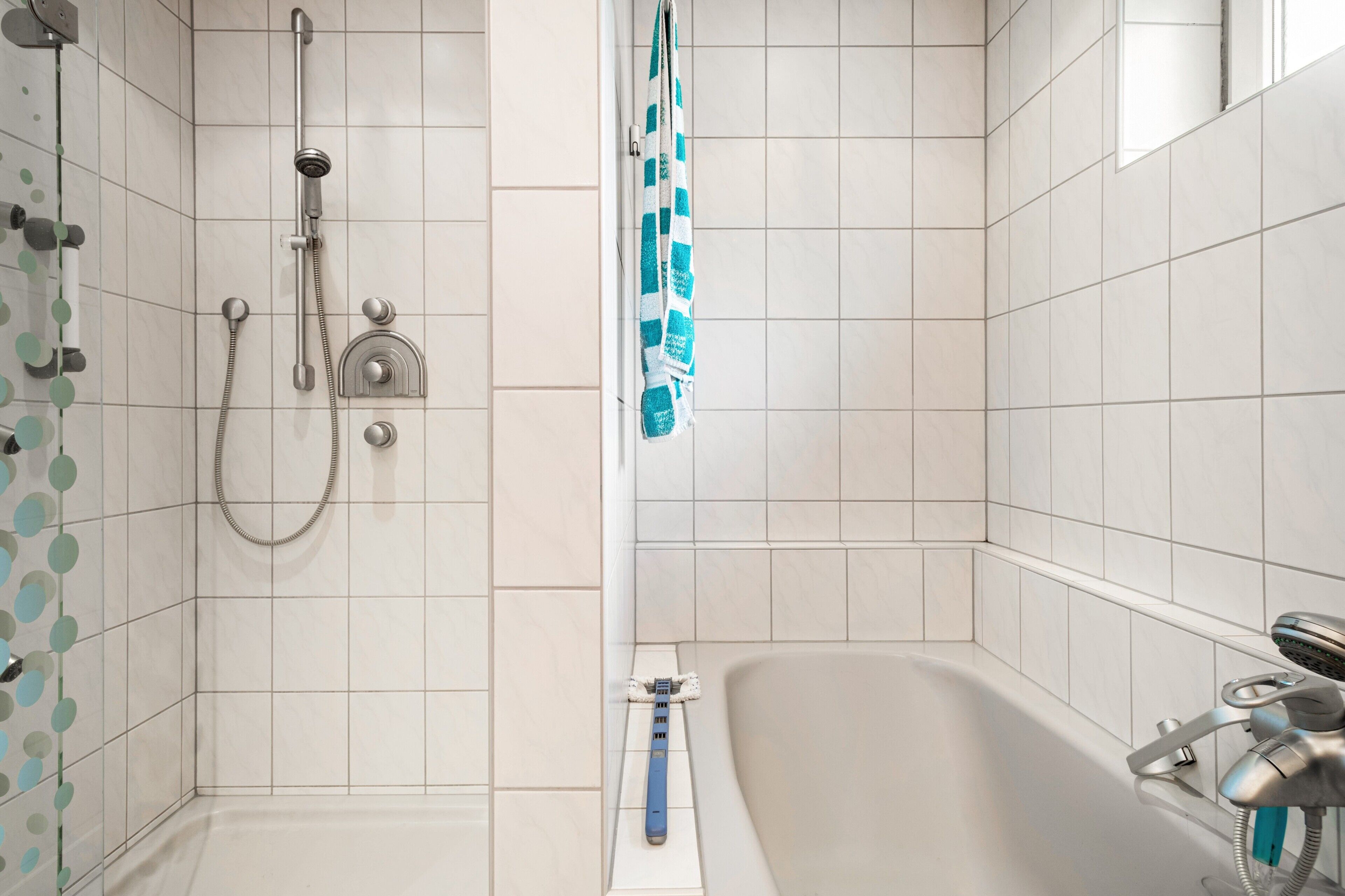 A bathroom with a shower, a bathtub, and a towel rack.