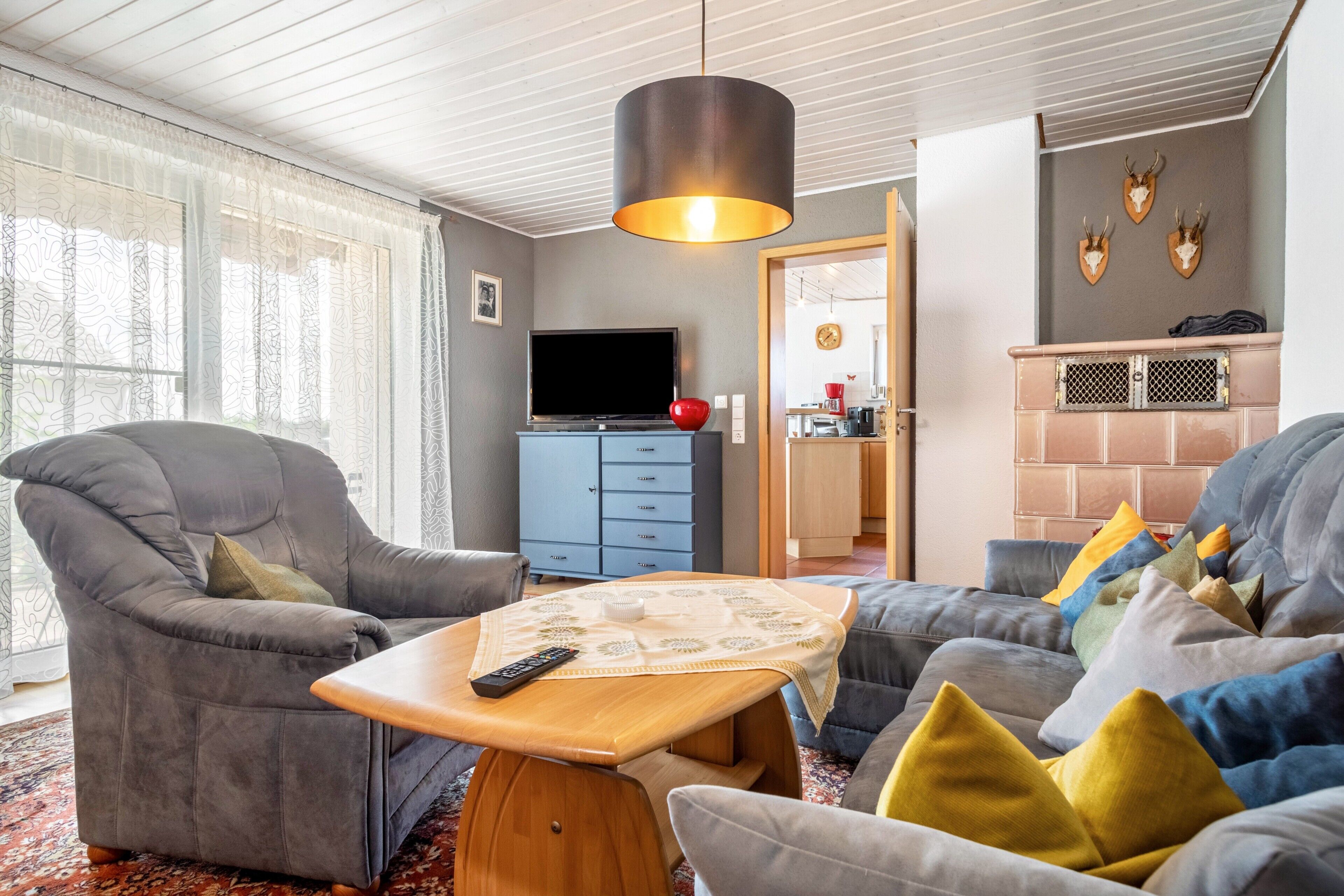 Een woonkamer met een bank, fauteuil en een televisie op een dressoir.
