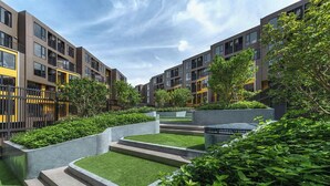 A modern residential building with multiple balconies, a landscaped courtyard with artificial grass, and a variety of trees and shrubs.