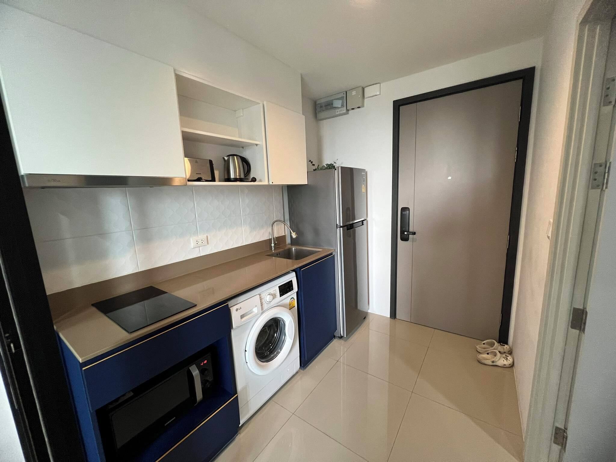 Eine kleine Küche mit Waschmaschine, Kühlschrank und Mikrowelle.