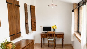 A room with a wooden desk, a chair, a television, a potted plant, and a window with curtains. - Casa Lilla - House with Garden near Venice (Veneto)