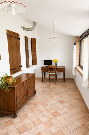 A room with a wooden desk, a chair, a television, a potted plant, and a window with curtains. - Casa Lilla - House with Garden near Venice (Veneto)