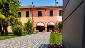 A building with a paved entrance, arched doorways, and a garden with various plants and flowers. - Casa Lilla - House with Garden near Venice (Veneto)