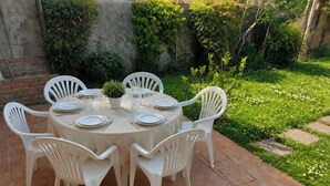 A round outdoor table with white plastic chairs, a potted plant, and set dining ware. - Casa Lilla - House with Garden near Venice (Veneto)