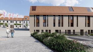 En moderne bygning med facade i mursten, store vinduer og en belagt gårdsplads.