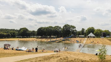 A lakeside park with sandy areas, a boat ramp, and a small building.