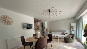 Una sala moderna con comedor, un sofá y una lámpara de techo original.