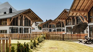 Un edifici de tipus xalet de fusta amb grans finestres, un balcó de fusta i un pati tancat.