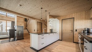 Een moderne keuken met houten wanden, een centraal eiland en een inbouwoven.