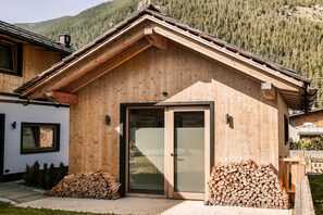 Una baita di legno con una porta vetrata, una scala in legno e una pila di legna da ardere.