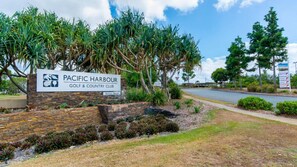 Schild für den Pacific Harbour Golf & Country Club mit angelegtem Garten und einer Straße im Hintergrund.