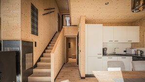 Een moderne keuken met houten keukenkastjes, een inbouwfornuis en een eethoek met een houten tafel.