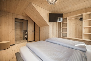 A modern bedroom with wooden walls, a TV mounted on the wall, and built-in shelving. - Chalet with mountain scenery Your Bichelbach (Bichlbach)