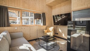 Een moderne woonkamer met een bank, een salontafel, een televisie en een fauteuil.