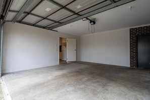 Ein leerer Raum mit Betonboden, einer Tür zu einer Küche und einer Ziegelwand.