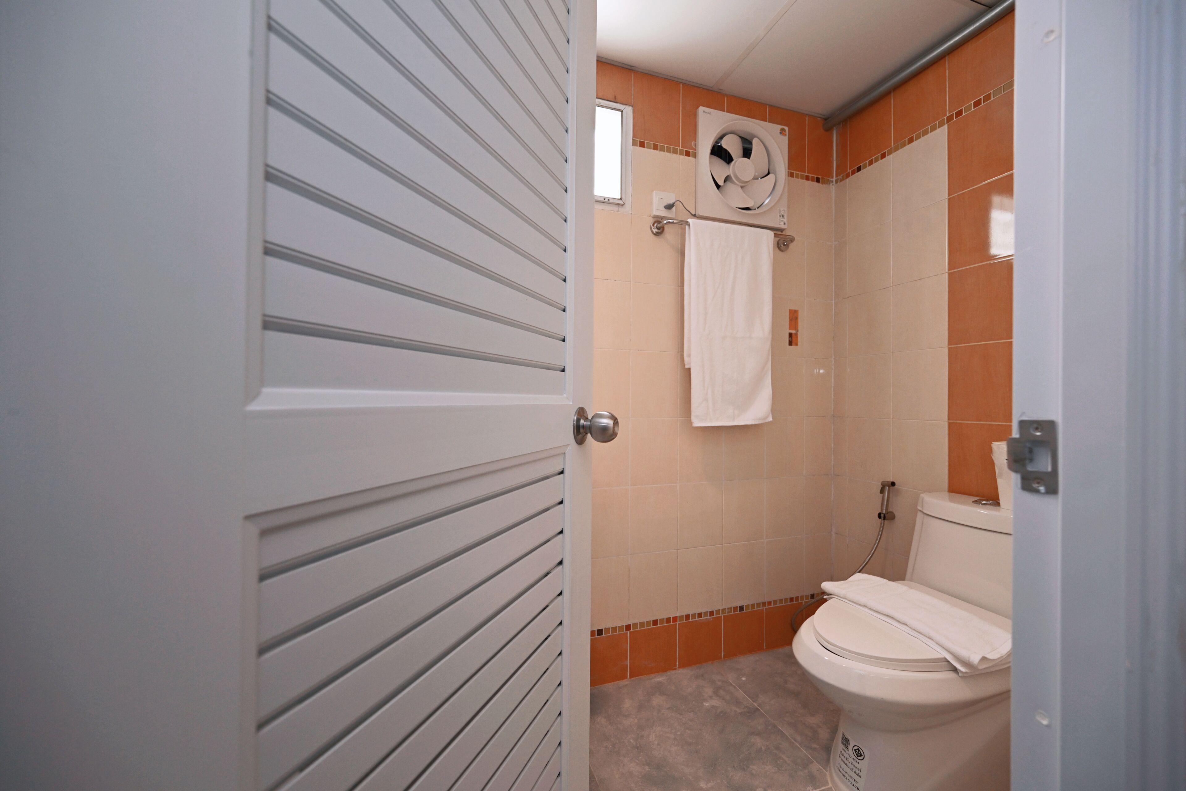 A bathroom with a toilet, a towel rack, and a fan.