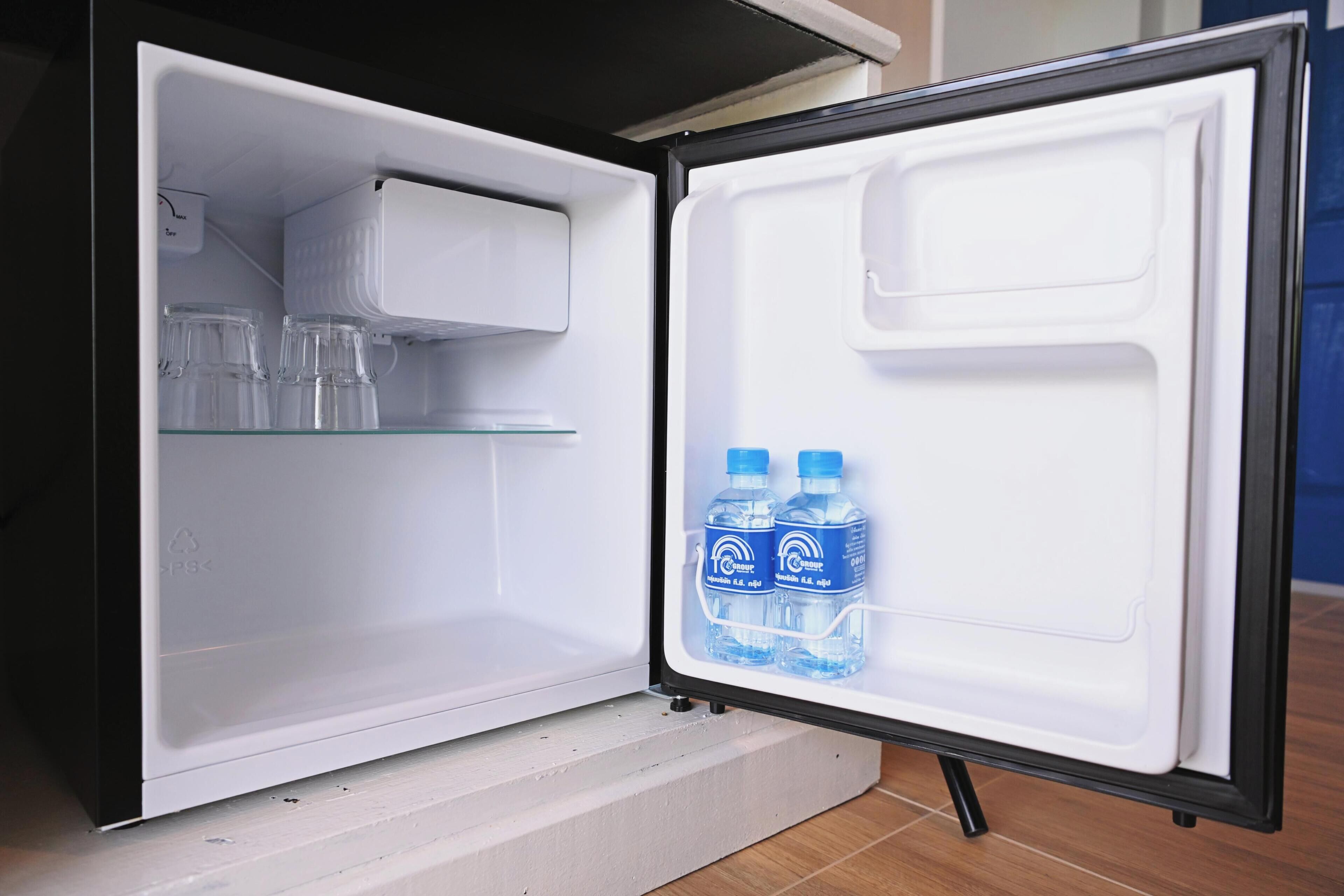 An open refrigerator with two water bottles on the door shelf and a glass container on the upper shelf.