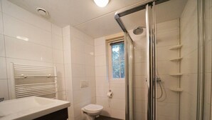 Un baño con ducha, inodoro y ventana.