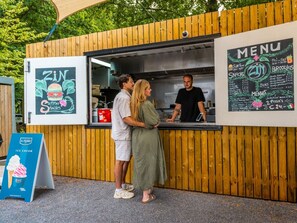 Een foodtruck met een menubord, een bord met ijs en een houten hek.