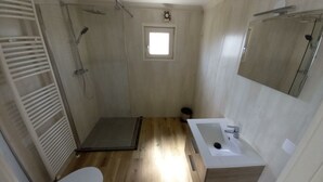 Un bany petit i funcional amb dutxa, vàter i rentapans.