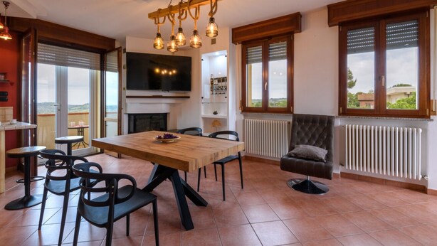 Un comedor amplio con una mesa de madera, sillas negras y una lámpara moderna.