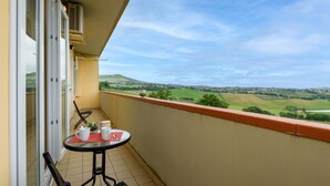 Un balcón con una mesa, sillas y vistas a un paisaje verde.