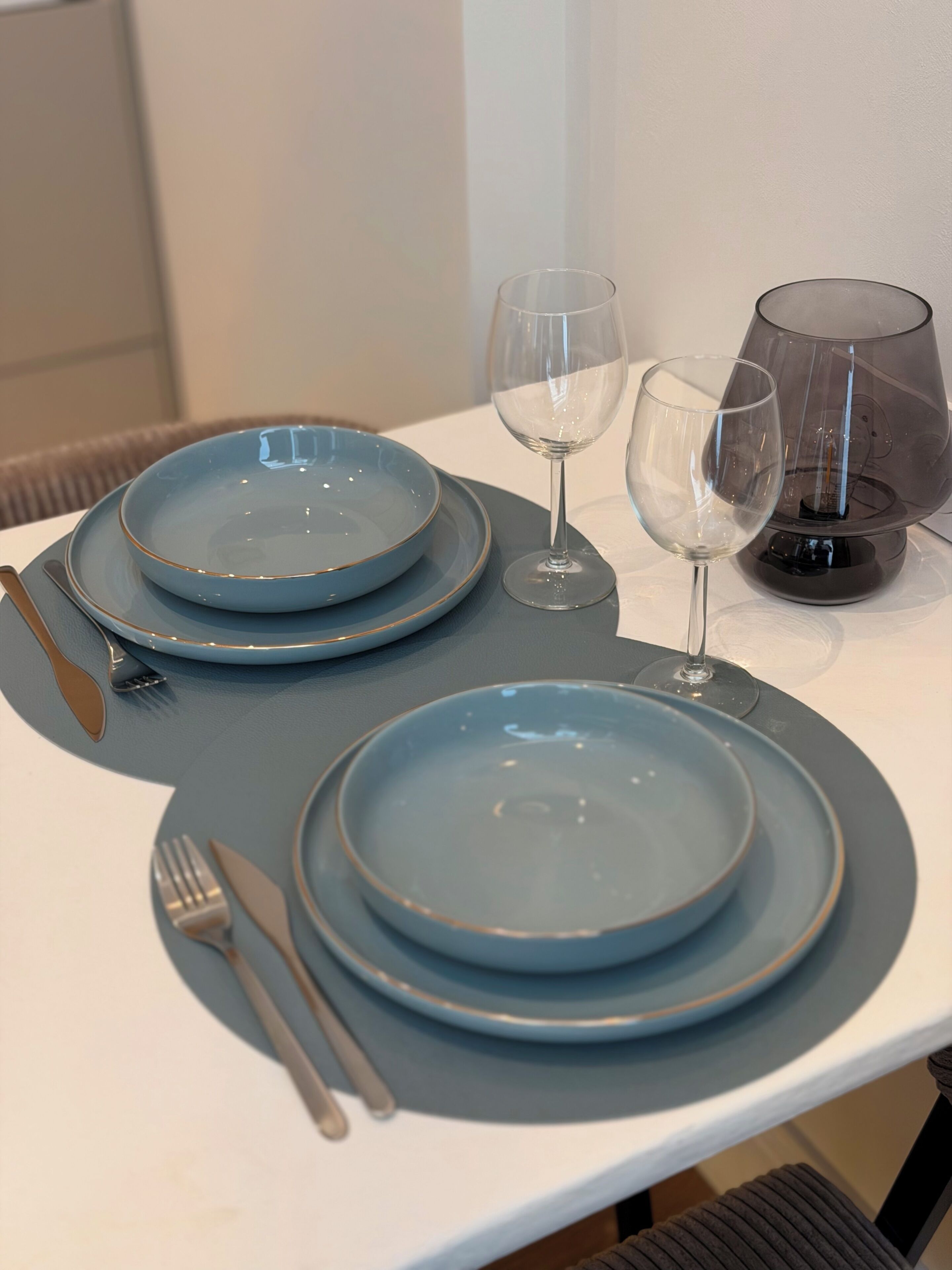 Mesa posta com pratos azuis, uma taça de vinho e um castiçal.