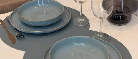 Mesa posta com pratos azuis, uma taça de vinho e um castiçal.