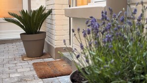 A potted plant, a welcome mat, and a window with a view of a building. - L'Échappée Malouine: Beach 3 min away + Private courtyard (Dunkerque)