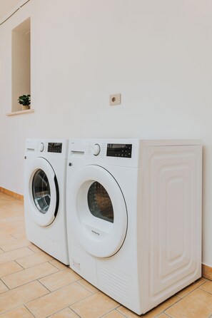 Two front-loading washing machines in a laundry room with tiled flooring and a small plant on the wall. - Casa Edoardo - Modern in Porta San Biagio (Lecce)