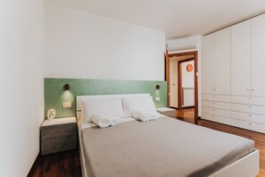 A bedroom with a bed, nightstands, a wardrobe, and a green accent wall. - Casa Edoardo - Modern in Porta San Biagio (Lecce)