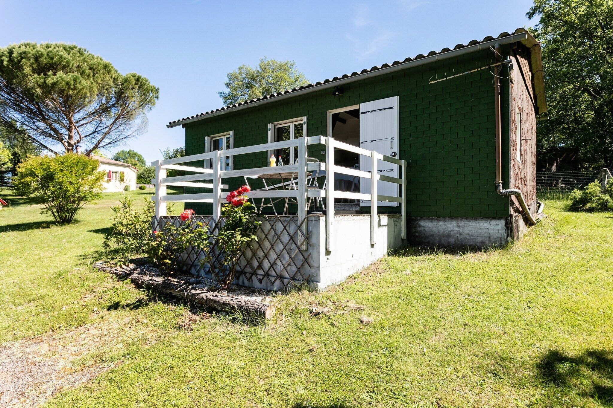 A green building with a white fence and a small porch.