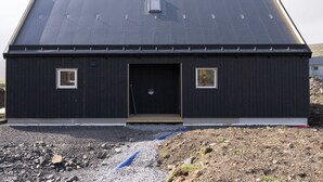 Un bâtiment d’un seul étage, à l’extérieur sombre, avec une porte centrale et deux petites fenêtres de chaque côté.