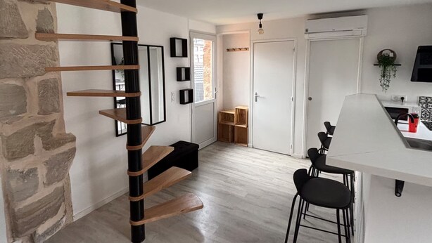 Una cocina moderna con una escalera en espiral, pared de piedra y decoración minimalista.