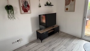 Un moderno salón con televisor de pantalla plana, piso de madera y decoración minimalista.