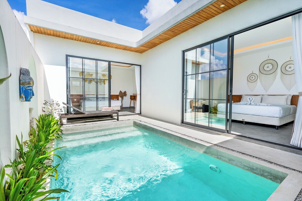 A modern pool area with glass walls, a white interior, and a wooden ceiling.